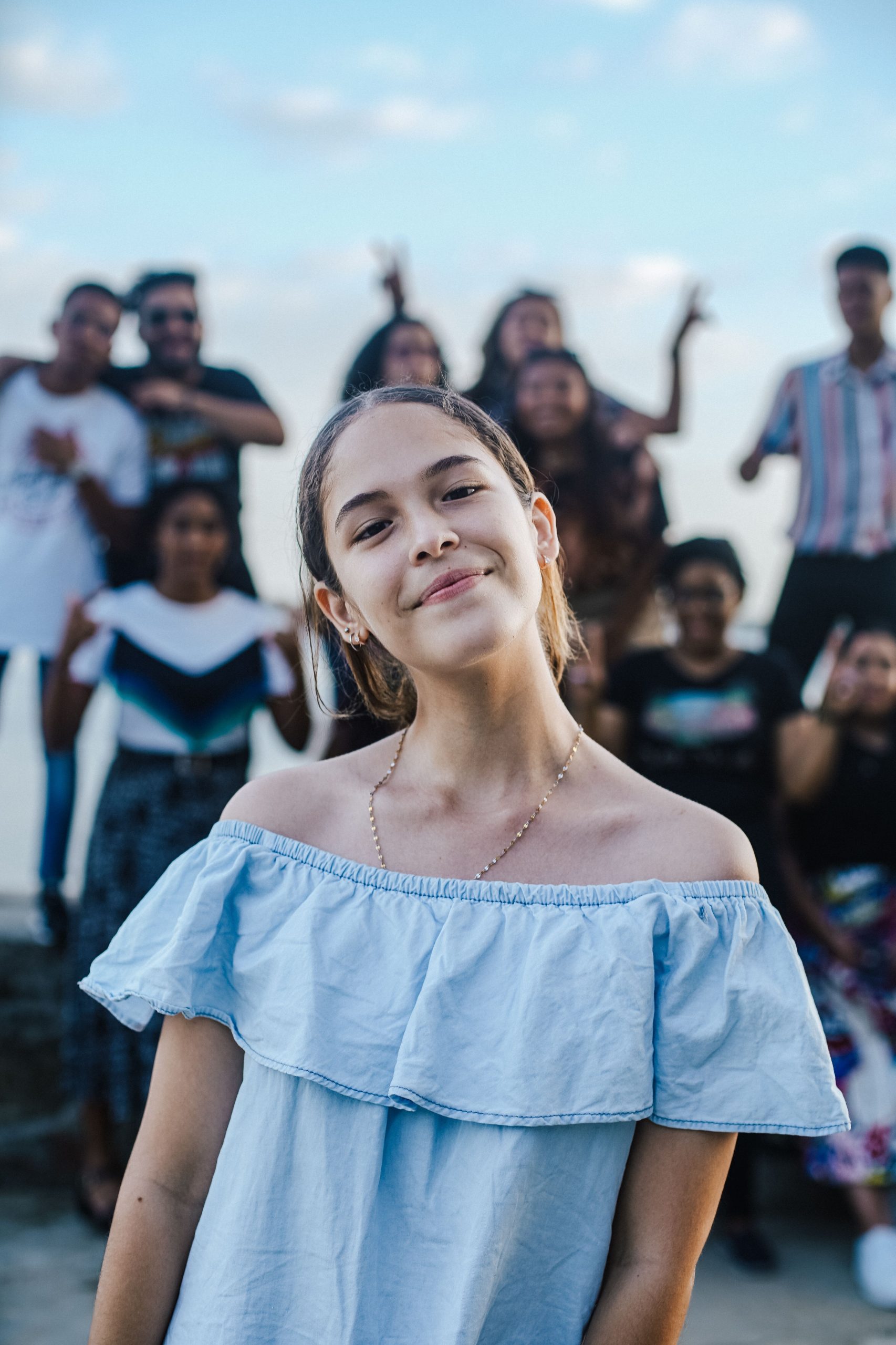 Home A cheerful teenage girl posing with friends in an outdoor setting, creating a joyful and lively atmosphere.