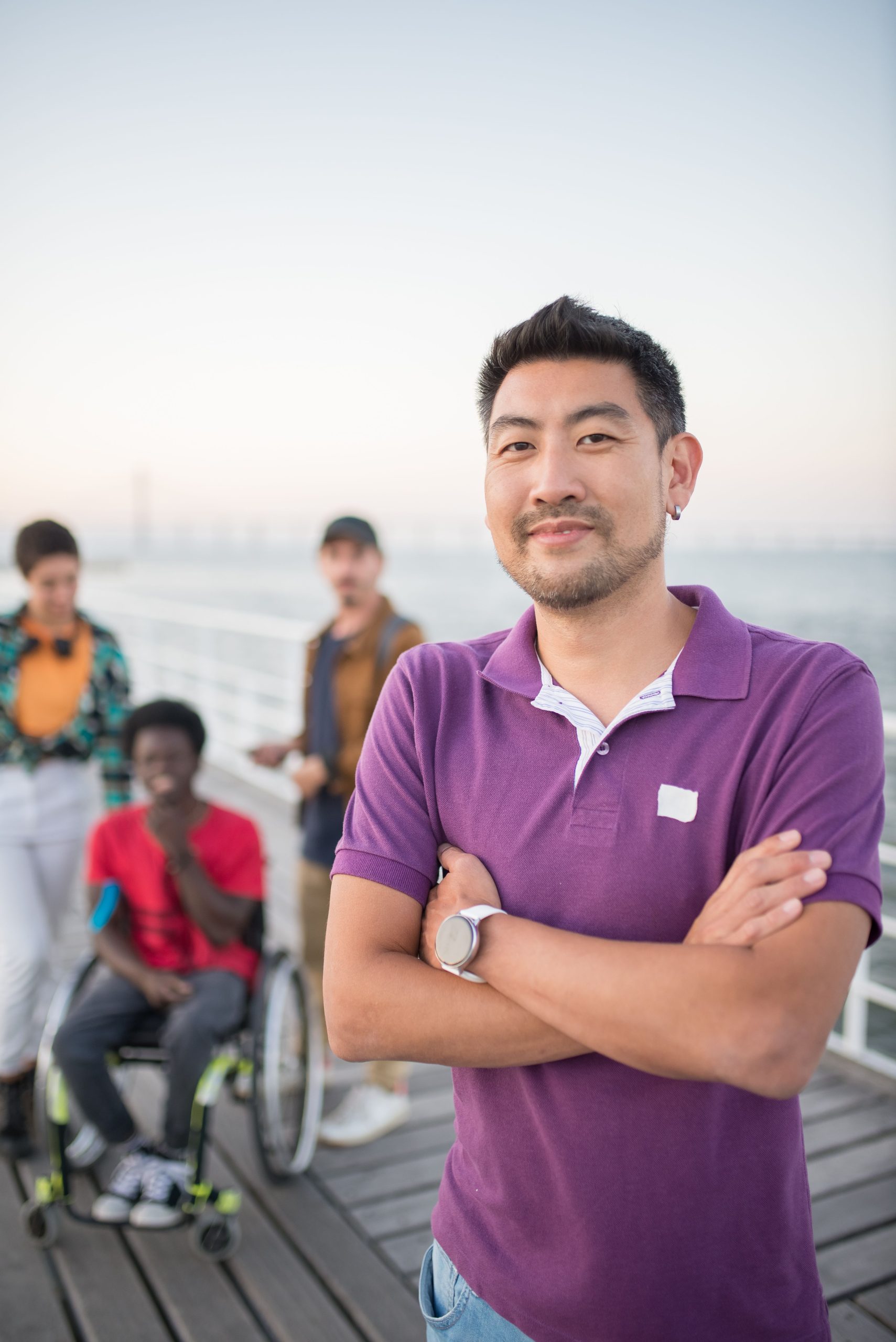 Home Smiling man in purple shirt with friends on a pier in Portugal.
